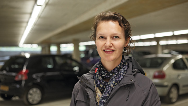  Žena sa usmieva pred autami v parkovacej garáži Eiteren osvetlenej spoločnosťou Philips Ligting. 
