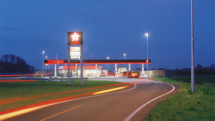 Za súmraku atraktívne osvetlená diaľničná čerpacia stanica spoločnosti Texaco – atraktívne exteriérové osvetlenie